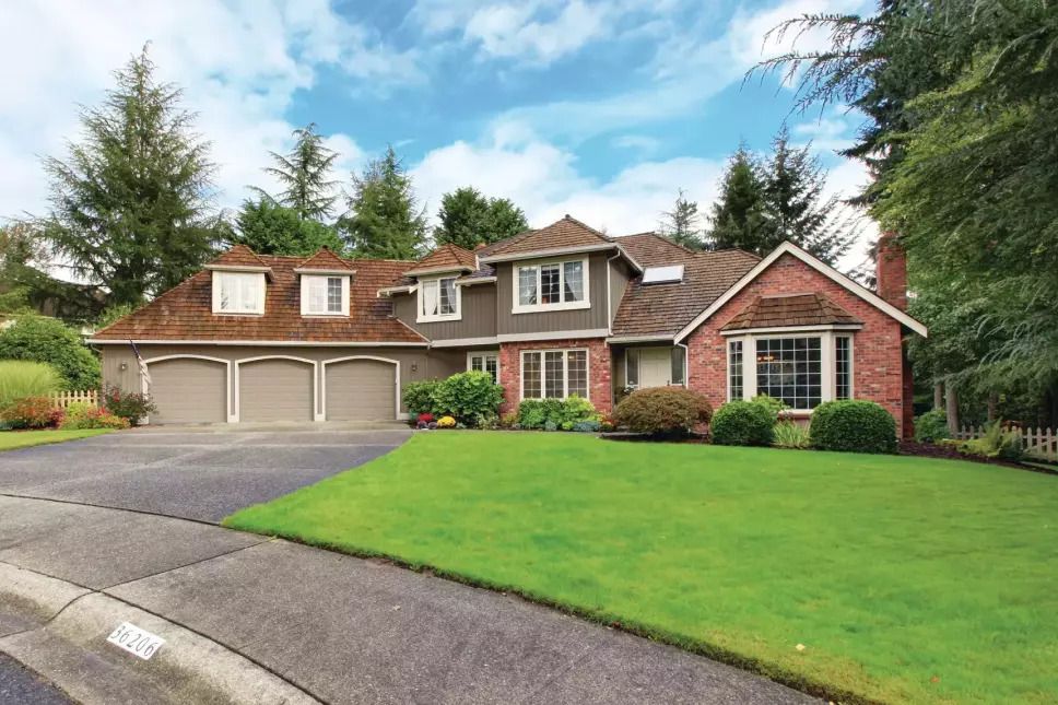 Yard of a two-story residential home with light green and gray exterior siding.