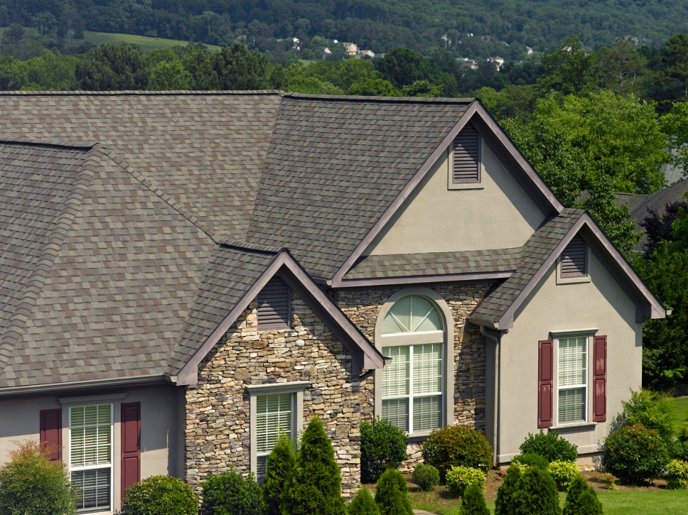 The exterior of a large home in Tennessee with stucco, stone, and red shudders enclosedwith a large,
