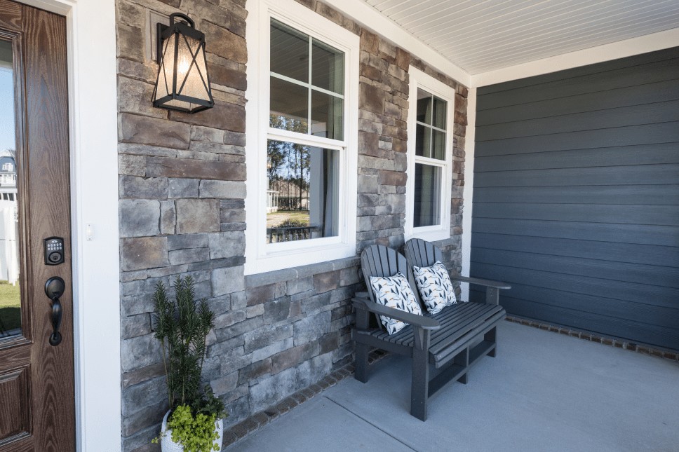 Energy-efficient windows by the front porch of a vinyl siding and stone home.