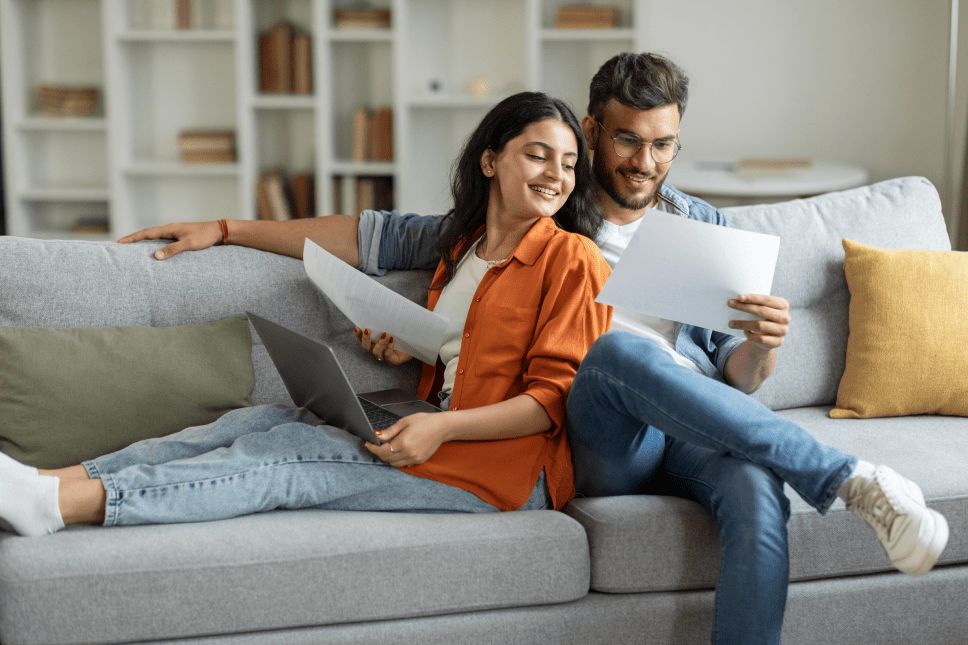 Couple seated on a couch reviewing documents together.
