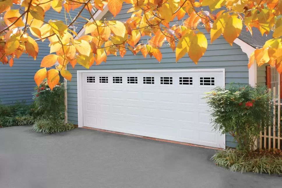 A white multi-car garage door on a home with gray siding.